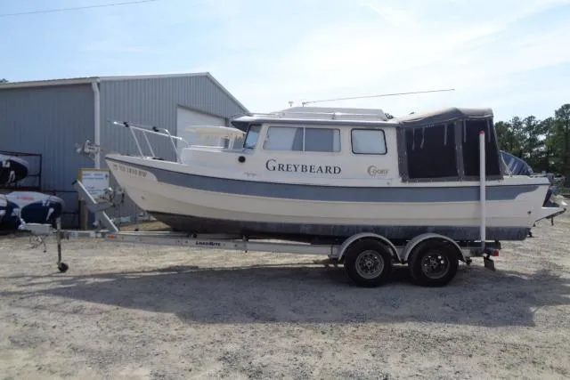Slide: The Image of 2004 C-Dory 22 Cruiser boat on trailer, parked outside a metal building. - 7