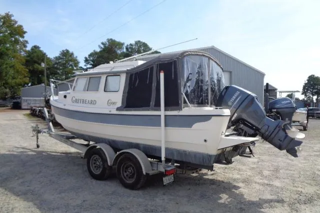 Slide: The Image of 2004 C-Dory 22 Cruiser boat on trailer, parked outdoors near a metal building. - 8
