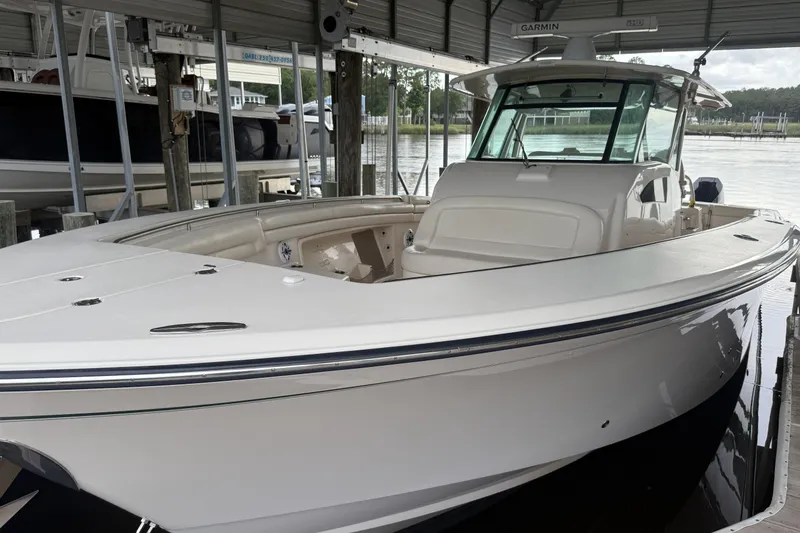Slide: The Image of 2015 Grady-White Canyon 376 boat interior with helm and seating under a covered dock. - 1