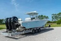 Slide: The Image of 2007 Fountain 38 Tournament Edition boat on trailer, triple engines, clear sky background. - 7