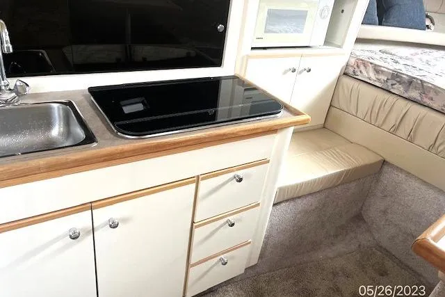Slide: The Image of 1997 Bayliner 2855 Ciera interior with kitchenette, sink, stove, and seating area. - 3