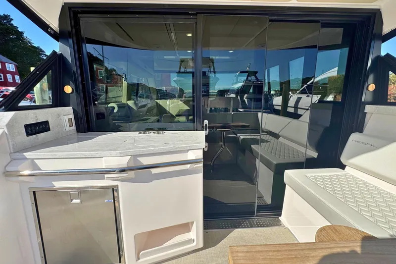 Slide: The Image of 2021 Regal 38 Grande Coupe interior with modern seating and kitchenette, dockside view. - 7