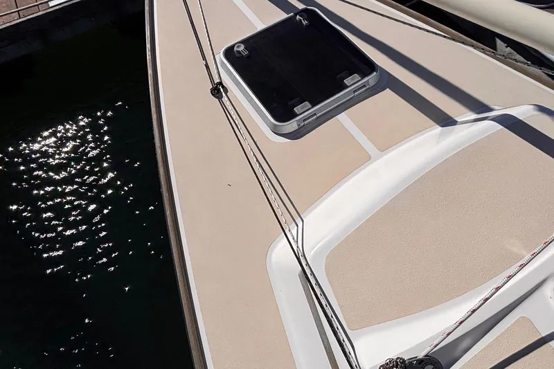 Slide: The Image of 2016 Alerion Express 28 sailboat deck with hatch, docked by shimmering water. - 10