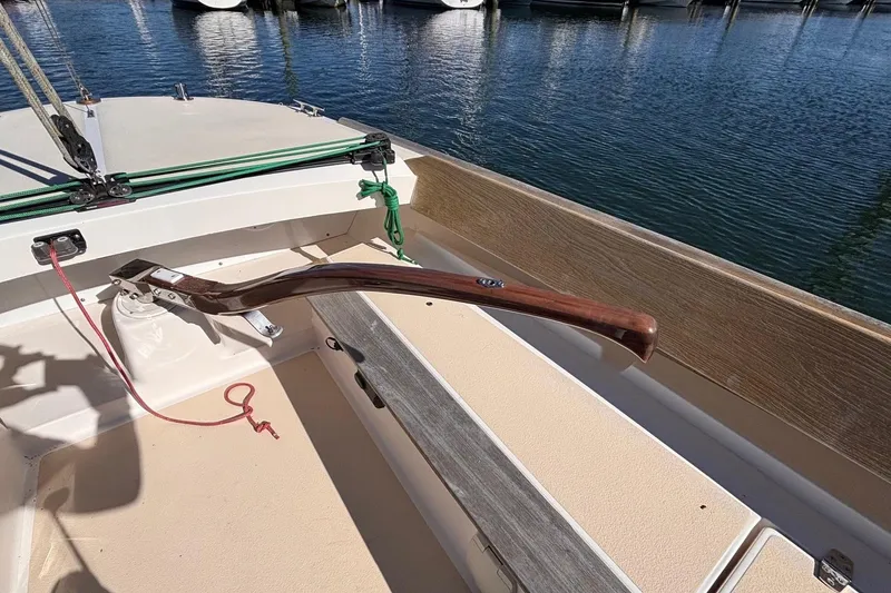 Slide: The Image of 2016 Alerion Express 28 sailboat cockpit with wooden tiller and marina view. - 17
