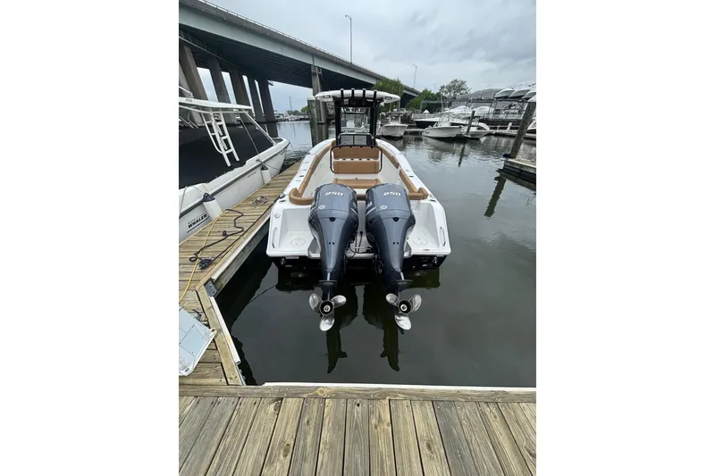 Slide: The Image of 2020 Sea Hunt Ultra 275 SE boat docked with twin engines, under cloudy sky. - 2