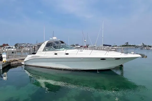 The Image of 1997 Sea Ray 400 Sundancer yacht docked in a marina, clear water, blue sky. - 1