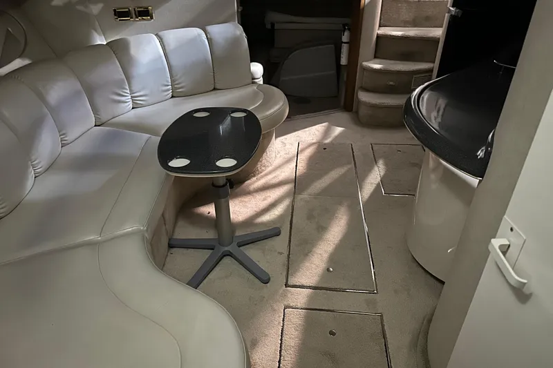 Slide: The Image of 1997 Sea Ray 400 Sundancer interior with beige seating, table, and carpeted flooring. - 79