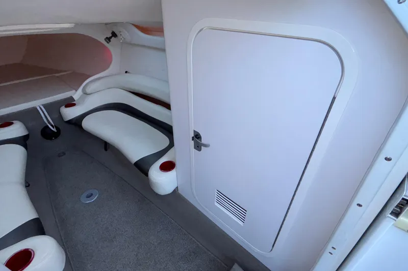 Slide: The Image of Interior of a 2001 Baja 33 Outlaw boat, featuring white seating and a cabin door. - 31