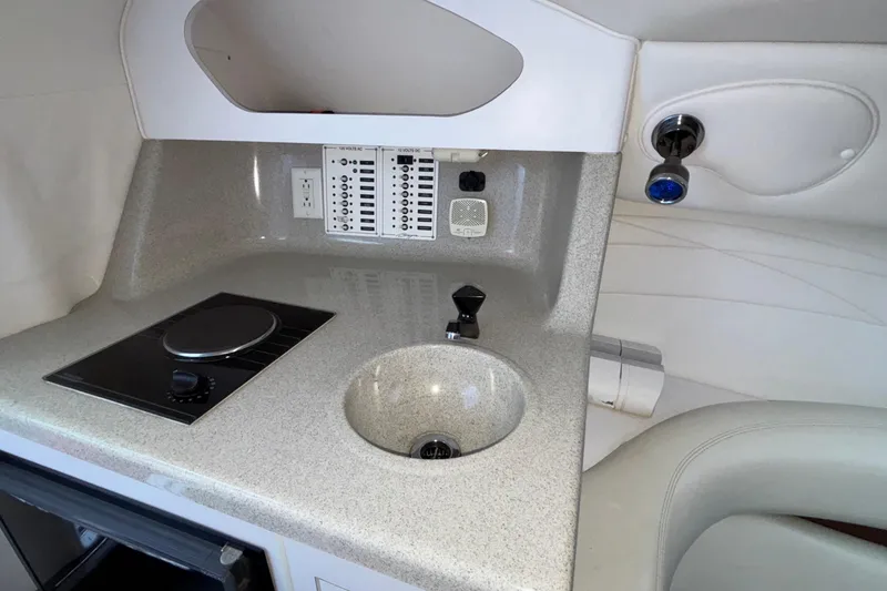 Slide: The Image of 2001 Baja 33 Outlaw boat interior with kitchenette, featuring a sink and stovetop. - 36