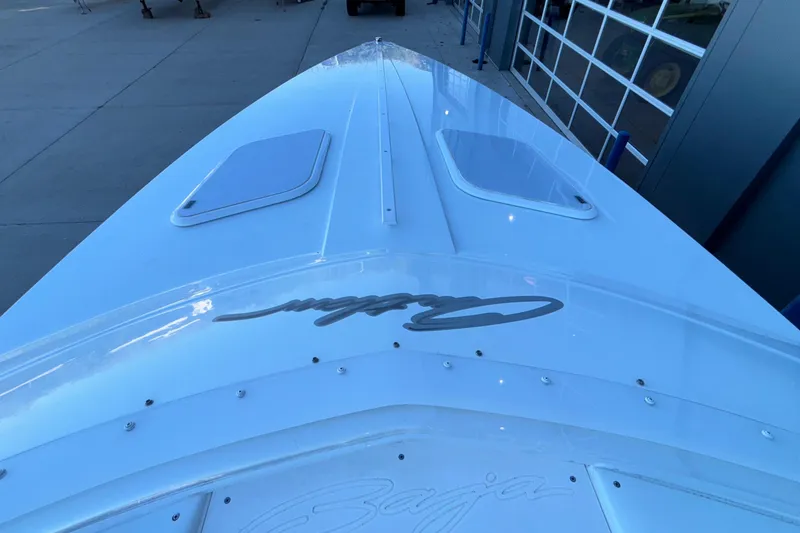Slide: The Image of 2001 Baja 33 Outlaw boat bow with sleek design and logo, docked near a garage. - 38