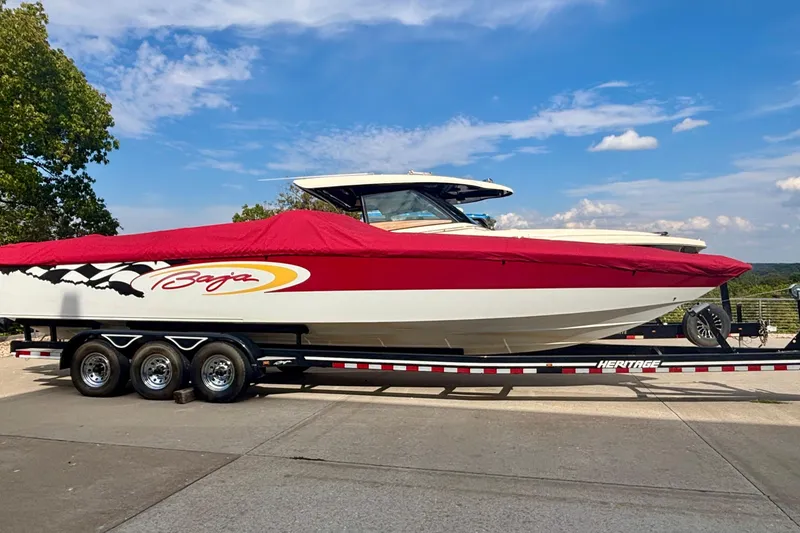 Slide: The Image of 2001 Baja 33 Outlaw speedboat on trailer, red cover, clear sky background. - 42