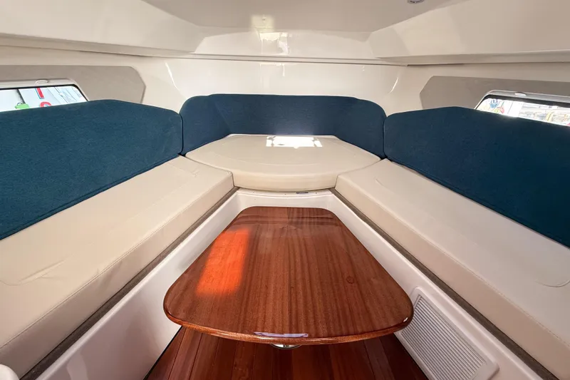 Slide: The Image of 2026 Pursuit OS 325 Offshore cabin interior with blue and beige seating, wooden table. - 12