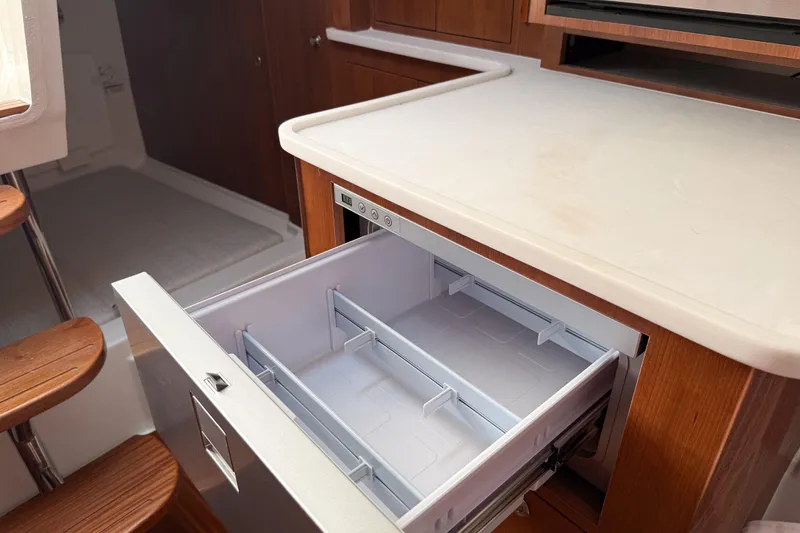 Slide: The Image of 2026 Pursuit OS 325 Offshore boat interior with open drawer and wooden cabinetry. - 13