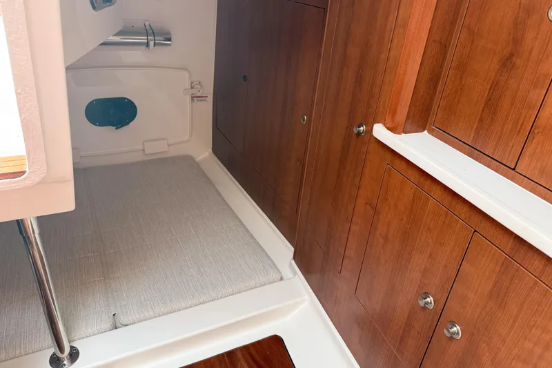 Slide: The Image of 2026 Pursuit OS 325 Offshore cabin interior with wooden cabinetry and cushioned seating. - 14