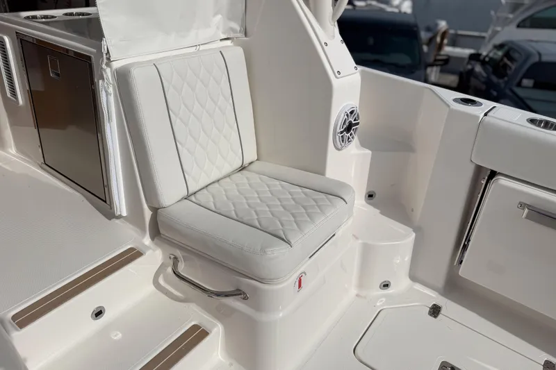 Slide: The Image of 2026 Pursuit OS 325 Offshore boat interior with white cushioned seating and stainless steel accents. - 5