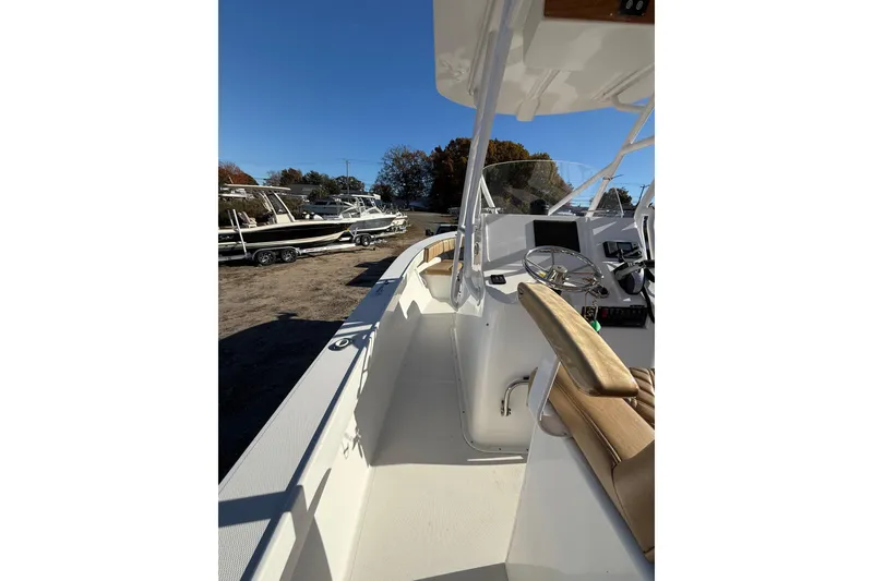 Slide: The Image of 2020 Bristol Harbor Vanquish boat interior with steering console and seating, docked outdoors. - 16