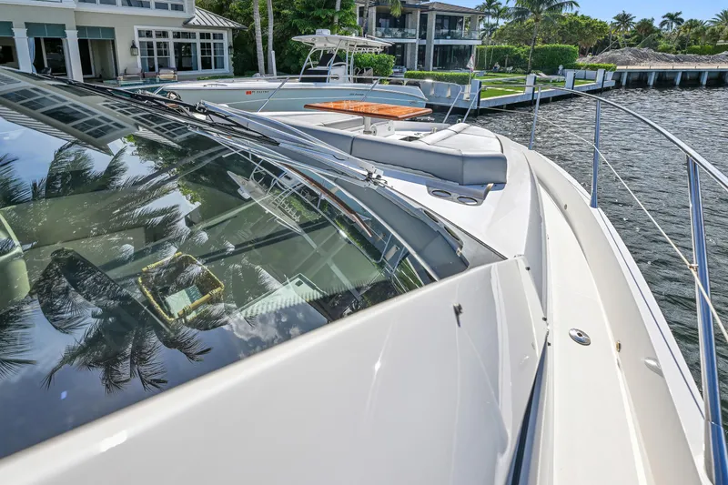 Slide: The Image of Sunseeker Manhattan 52 yacht, 2020 model, docked by waterfront homes. - 10