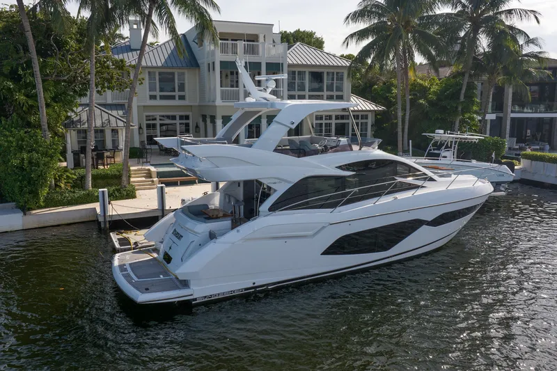Slide: The Image of 2020 Sunseeker Manhattan 52 yacht docked by waterfront home, surrounded by palm trees. - 3