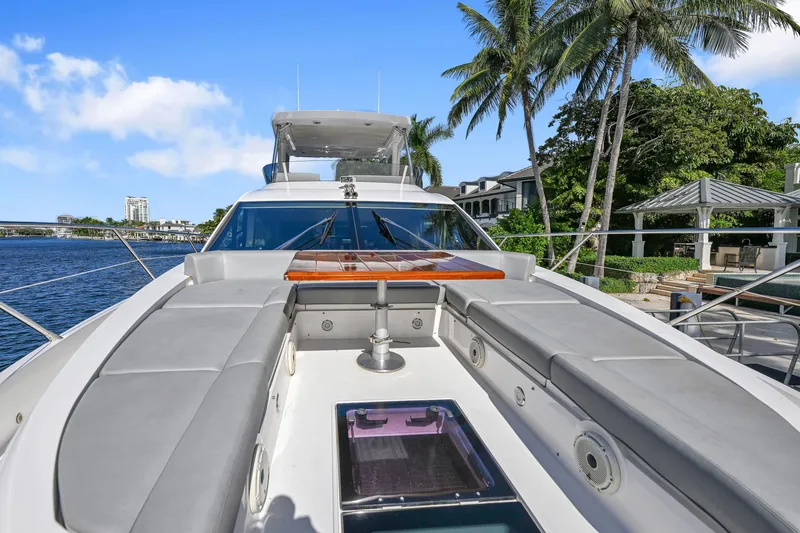 Slide: The Image of 2020 Sunseeker Manhattan 52 yacht with spacious deck, docked near palm trees and waterfront homes. - 8