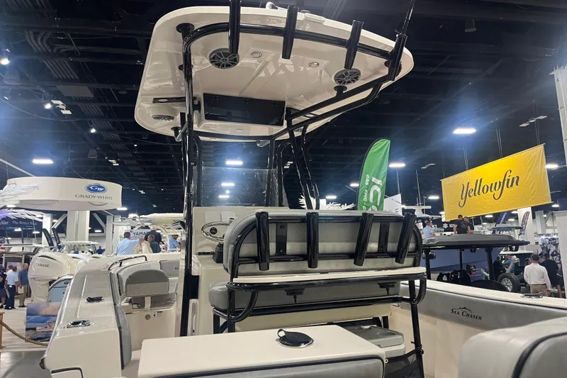 Slide: The Image of 2025 Sea Chaser 24 HFC boat displayed at indoor boat show with various brand banners. - 4