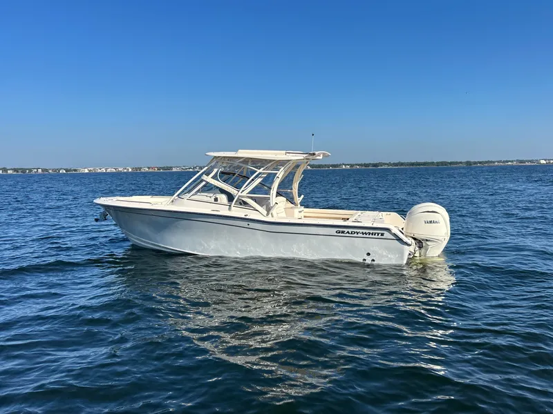 Slide: The Image of A 2026 Grady-White Freedom 275 boat floats on calm water under a clear sky. - 2