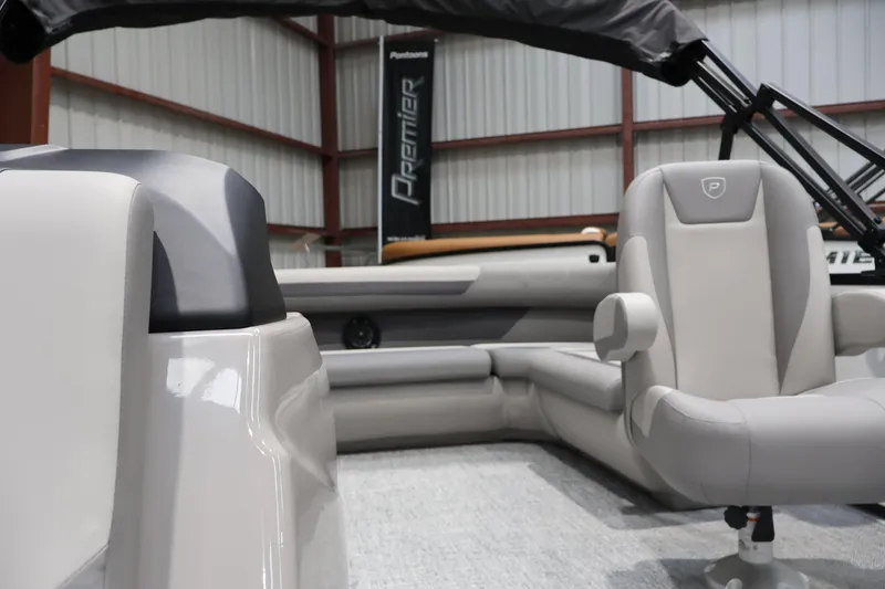 Slide: The Image of 2026 Premier 200 Sunscape RF pontoon boat interior with plush seating in a showroom. - 40