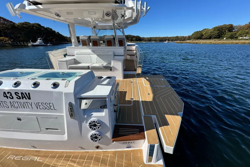 Slide: The Image of 2025 Regal 43 SAV sports activity vessel on serene water, showcasing luxury deck and seating. - 15