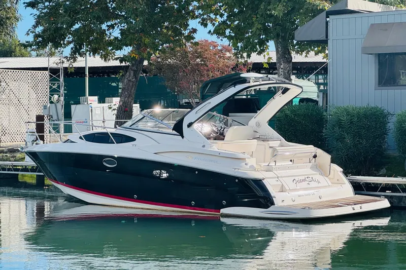The Image of 2006 Regal 3360 Window Express boat docked near trees and building. - 0