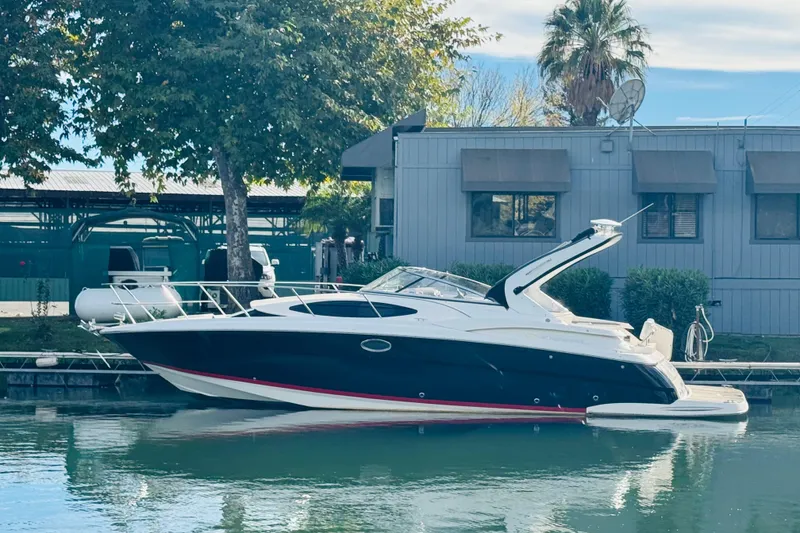 Slide: The Image of 2006 Regal 3360 Window Express boat docked by a building, surrounded by trees. - 3