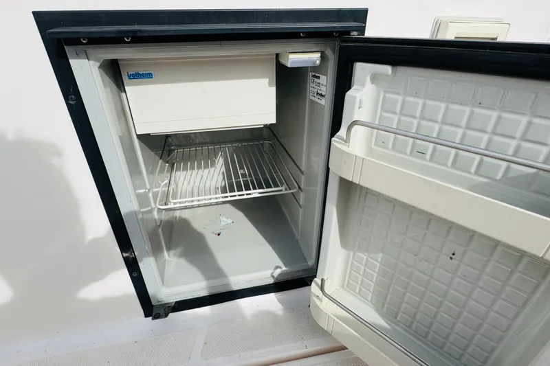 Slide: The Image of Open fridge on 2006 Regal 3360 Window Express boat, showing interior shelves. - 33