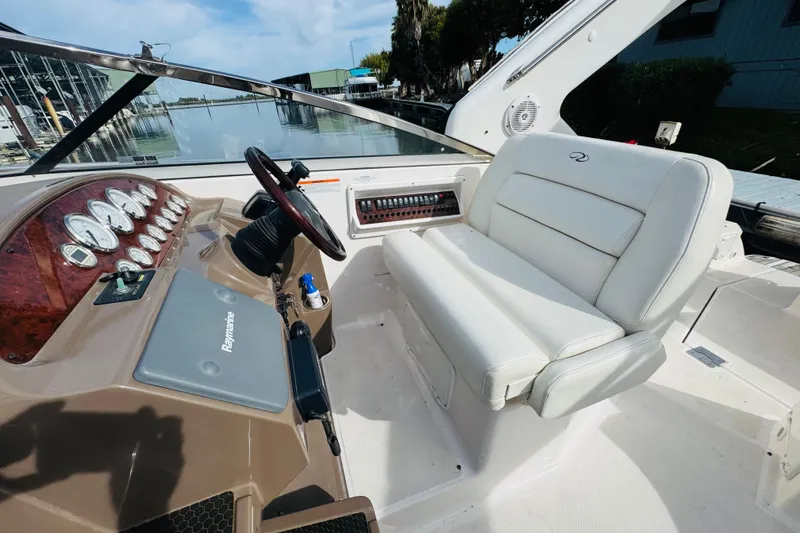 Slide: The Image of 2006 Regal 3360 Window Express boat cockpit with steering wheel and white seating. - 35