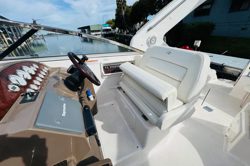 Slide: The Image of 2006 Regal 3360 Window Express boat cockpit with steering wheel and white seating. - 36