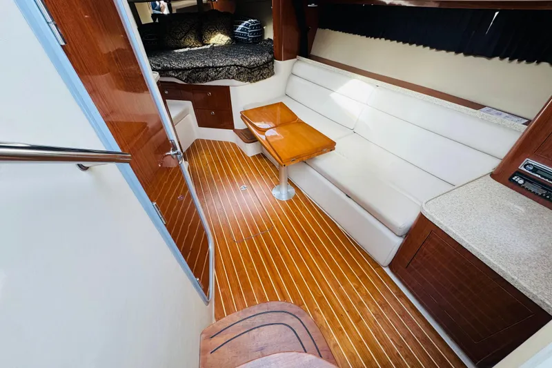 Slide: The Image of 2006 Regal 3360 Window Express interior with wood flooring, white seating, and compact table. - 42