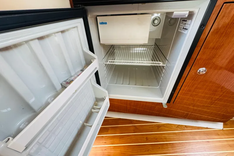 Slide: The Image of Open mini fridge inside 2006 Regal 3360 Window Express boat cabin. - 49