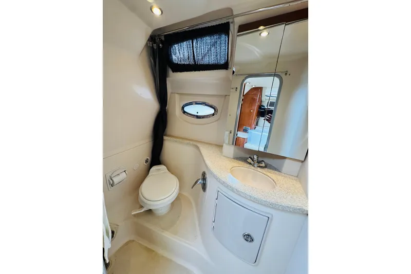 Slide: The Image of 2006 Regal 3360 Window Express yacht bathroom with toilet, sink, mirror, and porthole window. - 56