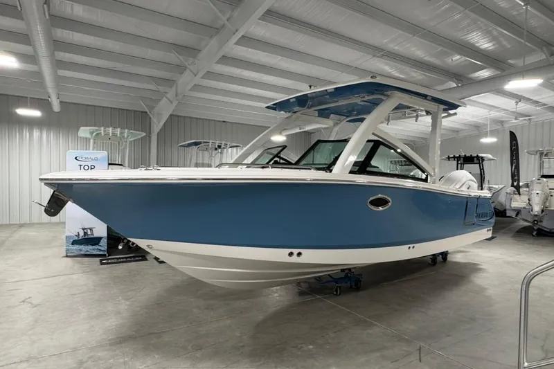The Image of 2026 Robalo R257 Dual Console boat in showroom, featuring sleek blue and white design. - 1