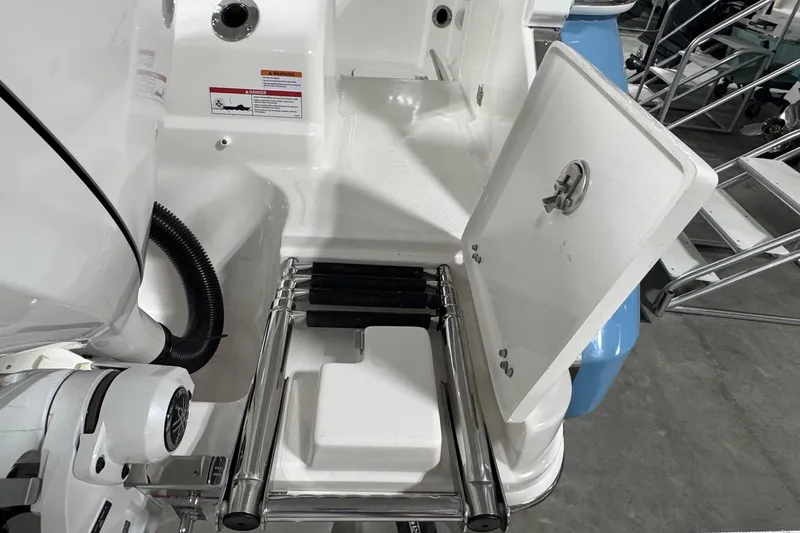 Slide: The Image of 2026 Robalo R257 Dual Console boat with open storage compartment and ladder. - 16
