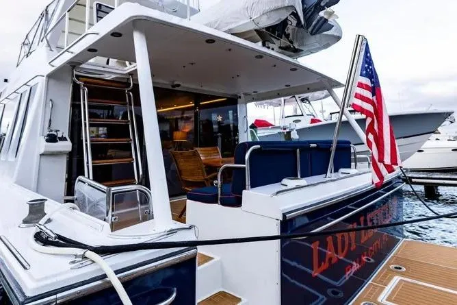 Slide: The Image of 2000 Pacific Mariner 65 Motoryacht docked, featuring American flag and elegant seating area. - 25