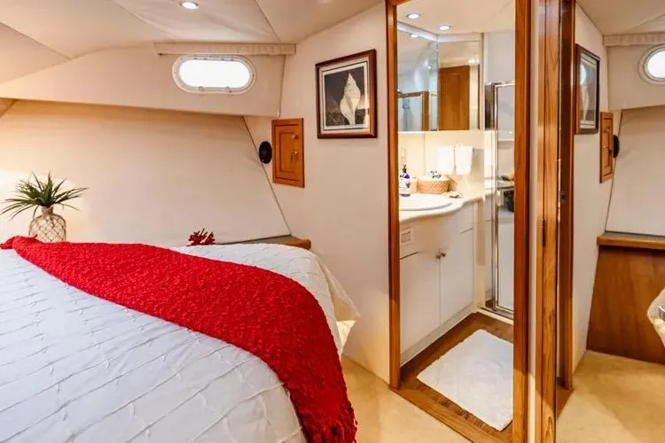 Slide: The Image of Luxurious 2000 Pacific Mariner 65 Motoryacht bedroom with ensuite bathroom, red accents, and elegant decor. - 59