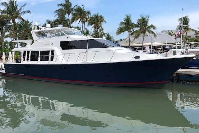 Slide: The Image of 2000 Pacific Mariner 65 Motoryacht docked, surrounded by palm trees and calm water. - 67