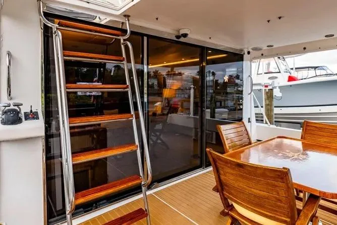 Slide: The Image of 2000 Pacific Mariner 65 Motoryacht deck with wooden table, chairs, and ladder. - 7