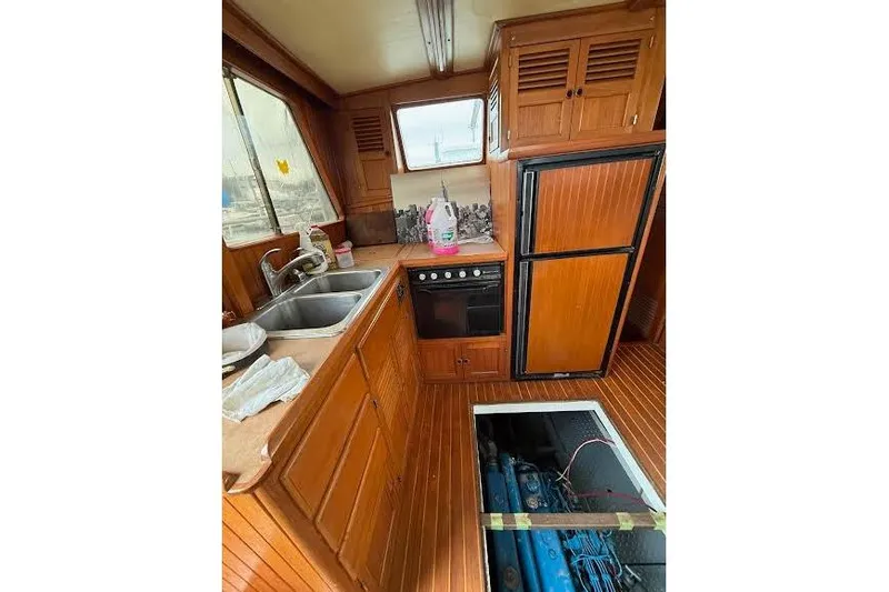 Slide: The Image of 1987 Monk 36 Trawler kitchen with wood cabinetry, double sink, stove, and open engine hatch. - 10