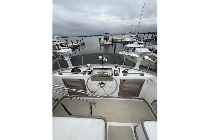 Slide: The Image of 1987 Monk 36 Trawler helm with marina view, featuring classic steering wheel and controls. - 2