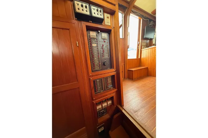 Slide: The Image of Control panel inside 1987 Monk 36 Trawler with wooden interior and electrical switches. - 23