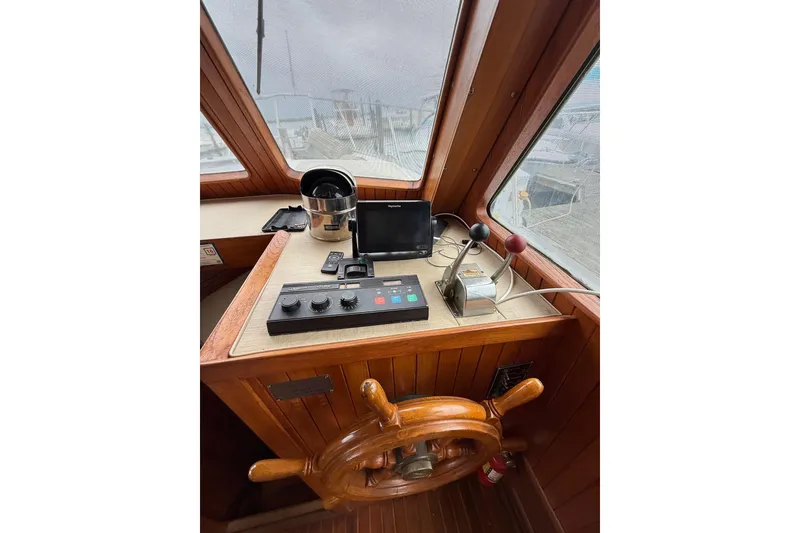 Slide: The Image of 1987 Monk 36 Trawler helm with wooden wheel, navigation controls, and windows. - 9