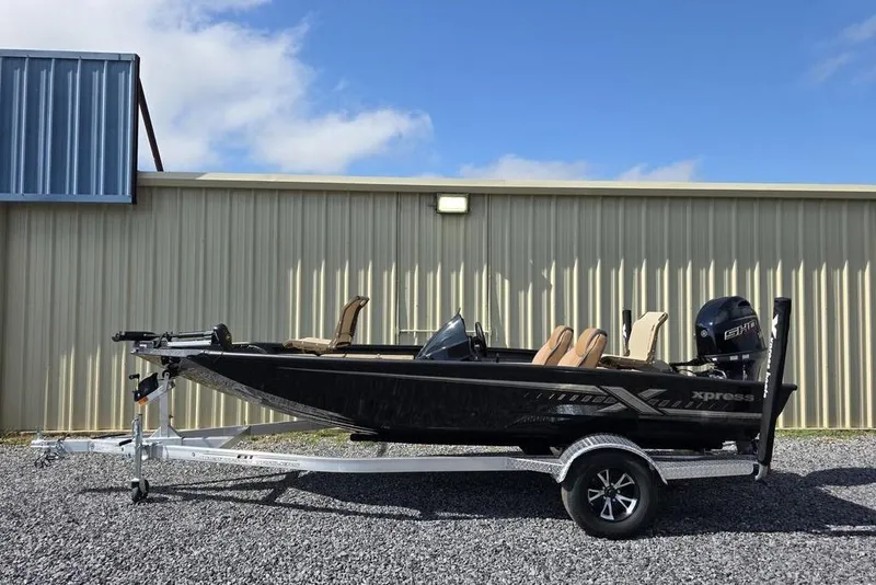 The Image of 2026 Xpress H17C Crappie boat on trailer, parked outside metal building. - 1