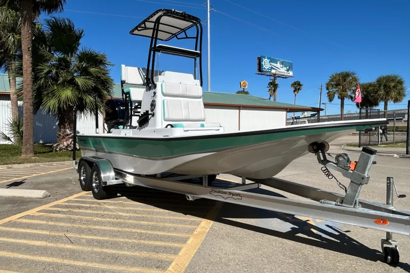 Slide: The Image of 2026 Shallow Sport 22 Sport boat on trailer, parked near palm trees under clear blue sky. - 4