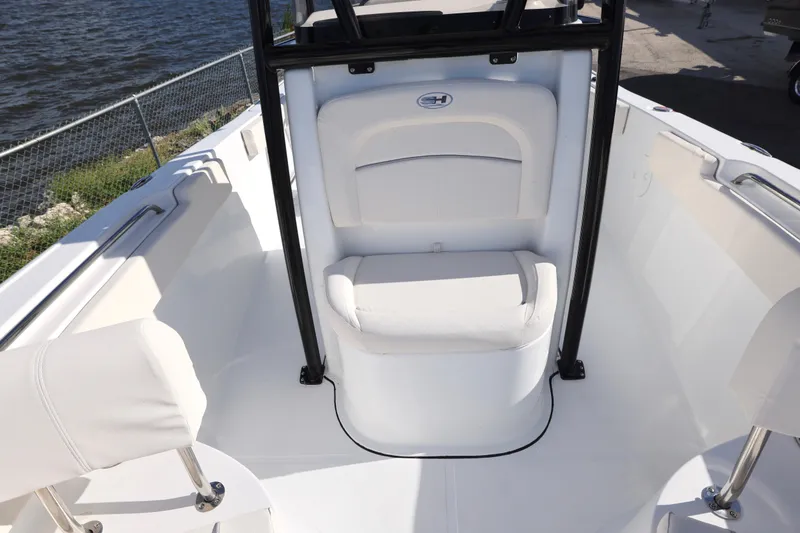 Slide: The Image of 2026 Sea Hunt Ultra 229 boat interior with seating and railing by the water. - 18