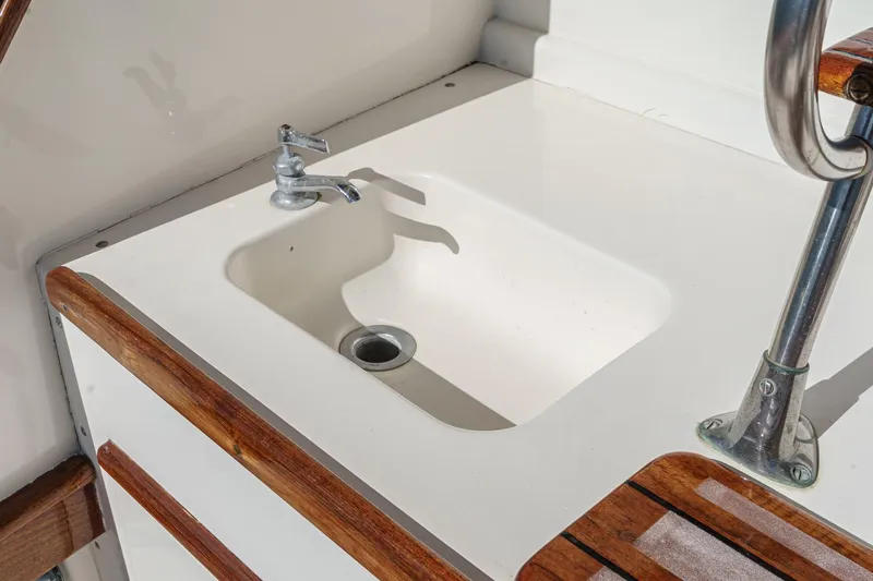 Slide: The Image of White sink with chrome faucet on a 1984 Post 43 boat, featuring wooden accents. - 40