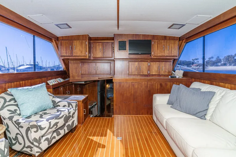 Slide: The Image of Luxurious 1984 Post 43 yacht interior with wood paneling, plush seating, and scenic marina views. - 45